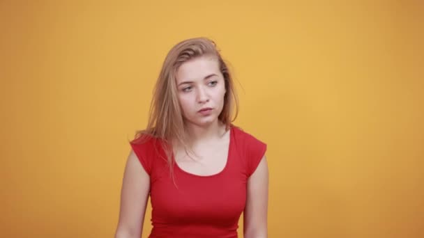 Jovem loira menina em vermelho t-shirt sobre isolado laranja fundo mostra emoções — Vídeo de Stock