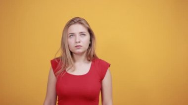 izole turuncu arka plan üzerinde kırmızı t-shirt genç sarışın kız duygularını gösterir