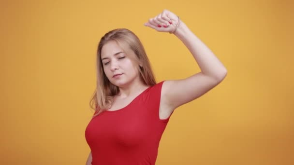Молодая блондинка в красной футболке на изолированном оранжевом фоне показывает эмоции — стоковое видео