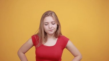 izole turuncu arka plan üzerinde kırmızı t-shirt genç sarışın kız duygularını gösterir