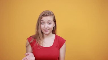 izole turuncu arka plan üzerinde kırmızı t-shirt genç sarışın kız duygularını gösterir