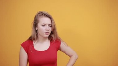 izole turuncu arka plan üzerinde kırmızı t-shirt genç sarışın kız duygularını gösterir
