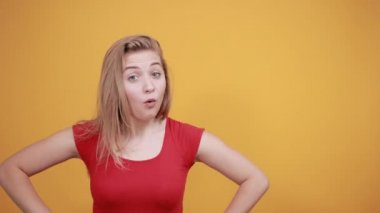 izole turuncu arka plan üzerinde kırmızı t-shirt genç sarışın kız duygularını gösterir