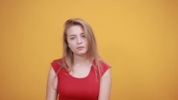 Junges blondes Mädchen in rotem T-Shirt über orangefarbenem Hintergrund zeigt Emotionen — Stockvideo