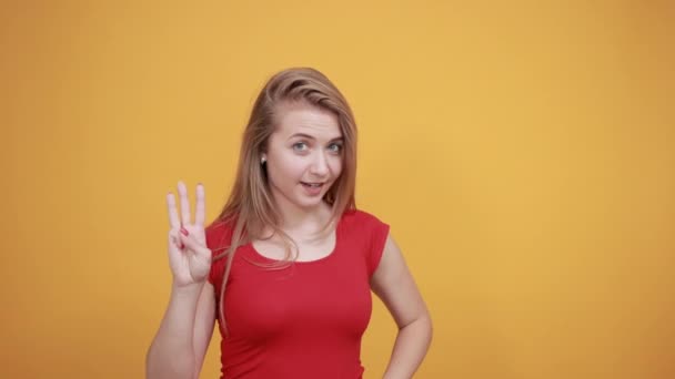 Joven rubia chica en rojo camiseta sobre aislado naranja fondo muestra emociones — Vídeo de stock