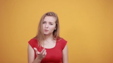 izole turuncu arka plan üzerinde kırmızı t-shirt genç sarışın kız duygularını gösterir