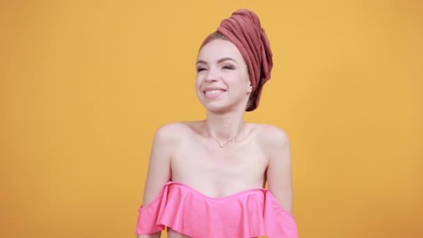 Mladá dívka s ručníkem na hlavě přes izolované oranžové pozadí vykazuje emoce — Stock video