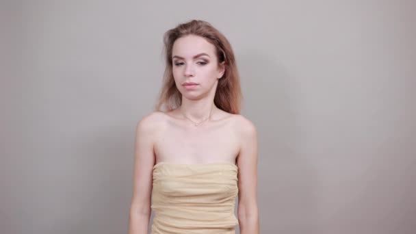Hermosa chica en camiseta beige sobre fondo blanco aislado muestra emociones — Vídeos de Stock
