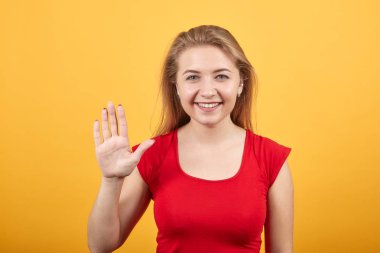 izole turuncu arka plan üzerinde kırmızı t-shirt genç sarışın kız duygularını gösterir