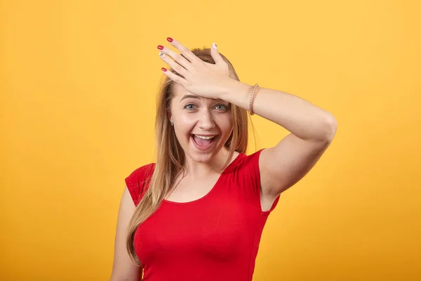 Молодая блондинка в красной футболке на изолированном оранжевом фоне показывает эмоции — стоковое фото
