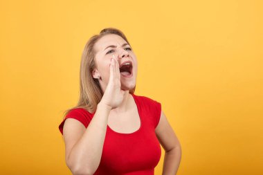 izole turuncu arka plan üzerinde kırmızı t-shirt genç sarışın kız duygularını gösterir