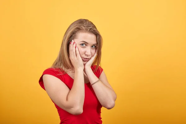 Jeune fille blonde en t-shirt rouge sur fond orange isolé montre des émotions — Photo