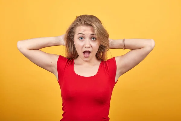 Fiatal szőke lány, piros t-shirt át elkülönített narancssárga háttér mutatja érzelmek — Stock Fotó