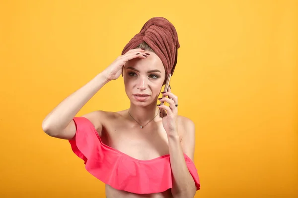 孤立したオレンジ色の背景の上に彼女の頭の上にタオルを持つ若い女の子は感情を示しています — ストック写真