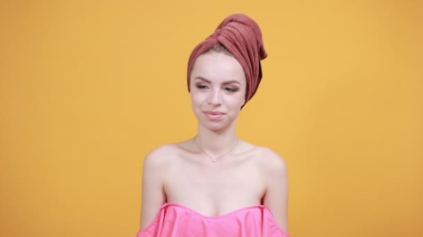 고립 된 오렌지 배경 위에 그녀의 머리에 수건을 가진 어린 소녀는 감정을 보여줍니다 — 비디오