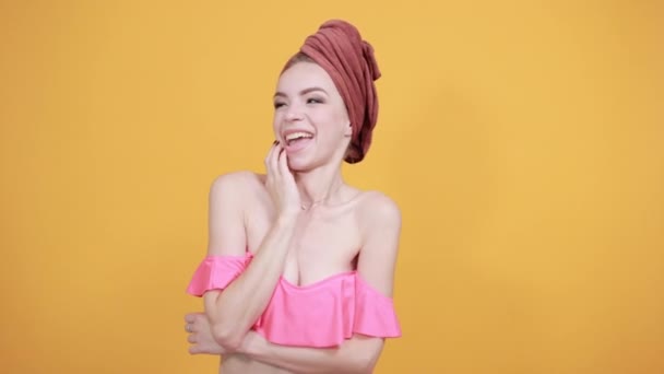 Mladá dívka s ručníkem na hlavě přes izolované oranžové pozadí vykazuje emoce — Stock video