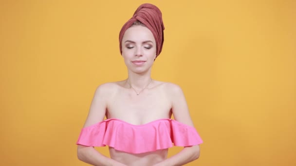 Молода дівчина з рушником на голові над ізольованим помаранчевим тлом показує емоції — стокове відео
