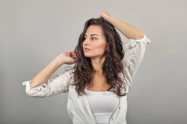 Gülümseyen genç model saçlarını tarıyor, moda pozları veriyor, elleri iplik gibi.