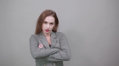 Göğsünde ayakta ve çapraz kollar var. Gri ceketli, çekici bir kadın.