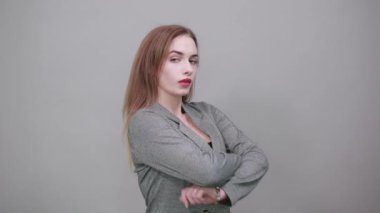 Göğsünde ayakta ve çapraz kollar var. Gri ceketli, çekici bir kadın.