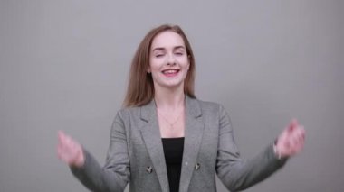 Kollar havaya, sevinçle başarı yumruklarını kutlayalım. Genç çekici kadın, gri.