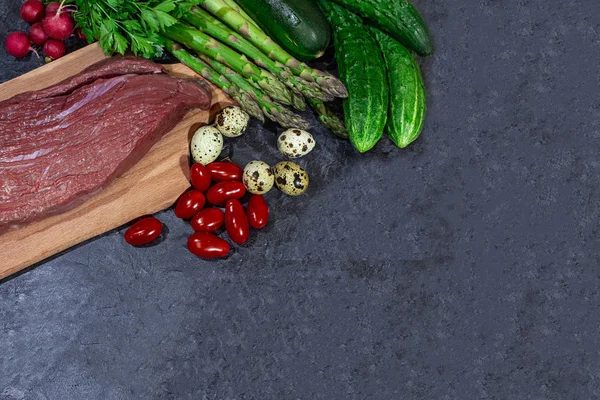 Siyah bir arka plan üzerinde sebze ile ahşap bir tahta üzerinde Sığır Eti.