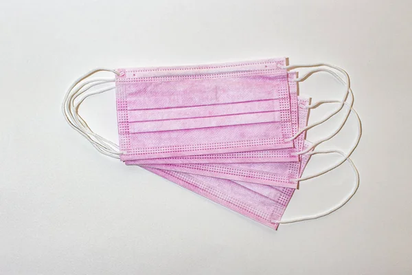 Beyaz arka planda pembe renk koruyucu tıbbi maske.