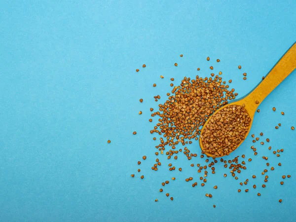 Mavi arka planda tahta kaşıkta karabuğday, sağ tarafta..