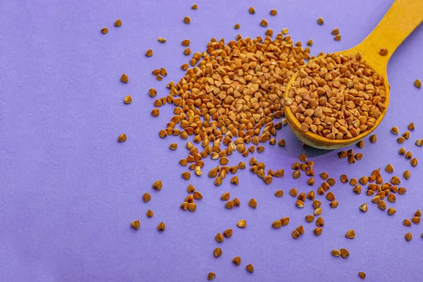 Mor arka planda tahta kaşıkta karabuğday, sağ tarafta..