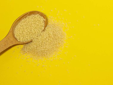 Kuskus sarı arka planda tahta bir kaşıkta homurdanıyor..