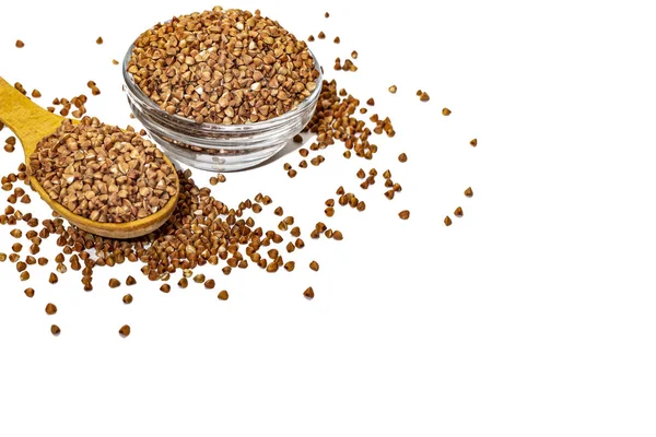 Cam bir kasede tahta kaşıkla karabuğday, beyaz arka planda karabuğday inliyor..