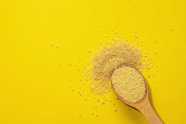 Kuskus sarı arka planda tahta bir kaşıkta homurdanıyor..