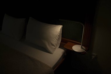 Tamamen karanlıkta, sadece başucundaki lamba parlar..