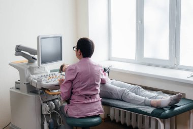 Hamile bir kız klinikte karnının ultrasonuna giriyor. Tıbbi muayene