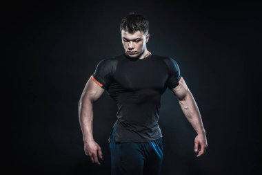 Stüdyoda siyah arka planda poz veren seksi genç bir atlet. Fitness, vücut geliştirme