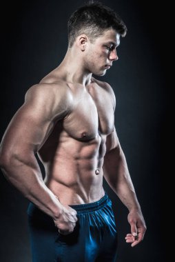 Stüdyoda siyah arka planda poz veren seksi genç bir atlet. Fitness, vücut geliştirme