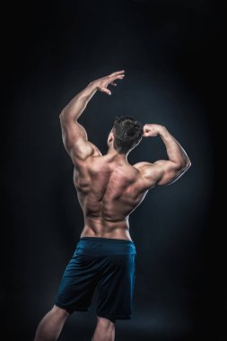 Stüdyoda siyah arka planda poz veren seksi genç bir atlet. Fitness, vücut geliştirme