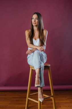 Stüdyoda sandalyede poz veren güzel seksi kız. Moda.