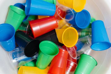 Yere saçılmış büyük renkli plastik bardaklar. Çevrenin insan atıklarıyla kirlenmesi