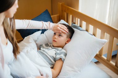Ateşi ve ateşi olan bir anne çocuğuna bakar. Hastalık ve sağlık hizmetleri