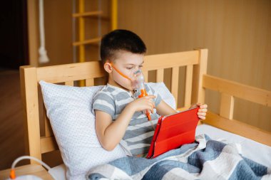 Bir çocuk akciğer solunumu sırasında tabletle oynuyor. İlaç ve bakım