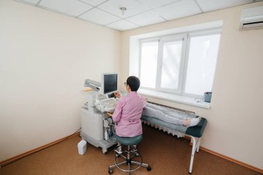 Hamile bir kız klinikte karnının ultrasonuna giriyor. Tıbbi muayene