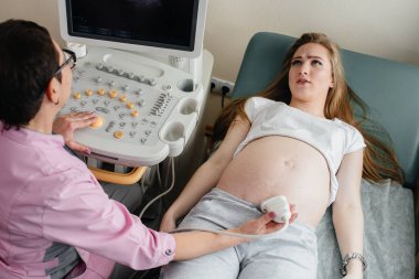 Hamile bir kız klinikte karnının ultrasonuna giriyor. Tıbbi muayene