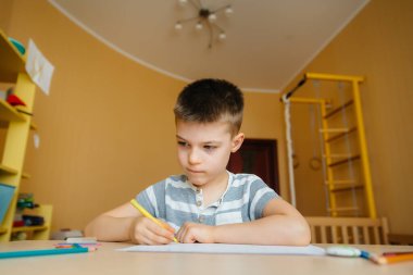 Okul çağındaki bir çocuk evde ödev yapar. Okulda eğitim.