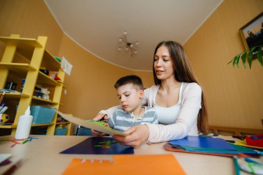 Genç bir anne evde oğluyla ev ödevi yapıyor. Ebeveynler ve eğitim