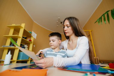 Genç bir anne evde oğluyla ev ödevi yapıyor. Ebeveynler ve eğitim