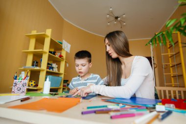 Genç bir anne evde oğluyla ev ödevi yapıyor. Ebeveynler ve eğitim