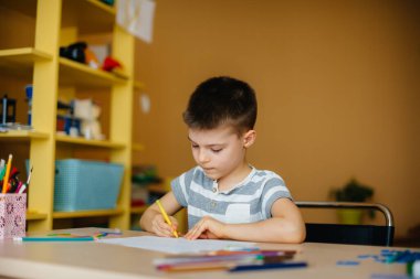 Okul çağındaki bir çocuk evde ödev yapar. Okulda eğitim.