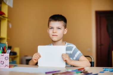 Okul çağındaki bir çocuk evde ödev yapar. Okulda eğitim.