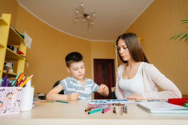 Genç bir anne evde oğluyla ev ödevi yapıyor. Ebeveynler ve eğitim